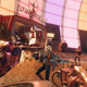 Two guns are pointed at masked assailants in front of a large neon sign.
